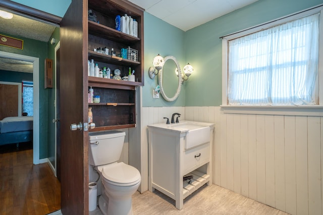 bathroom with wainscoting, vanity, toilet, and wood finished floors