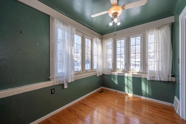 unfurnished room featuring visible vents, baseboards, wood finished floors, and a textured wall