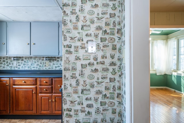 interior space featuring baseboards, wood finished floors, and wallpapered walls