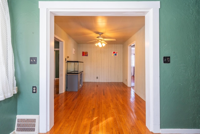 corridor featuring visible vents, wood finished floors, and a textured wall