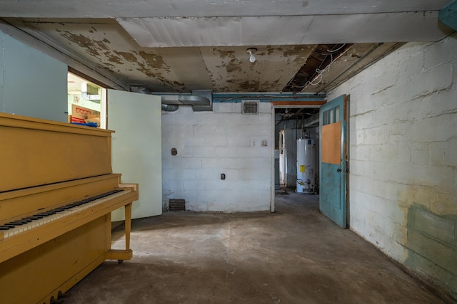 unfinished below grade area with concrete block wall, water heater, and visible vents