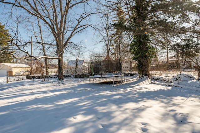 yard layered in snow with a trampoline