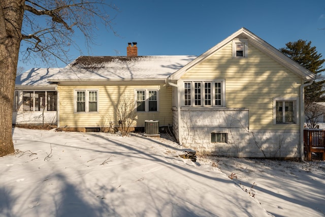 snow covered house featuring a chimney and central AC