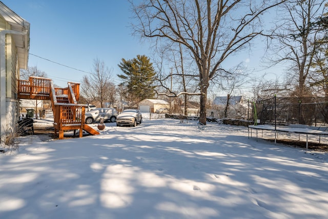 snowy yard featuring a trampoline and a playground