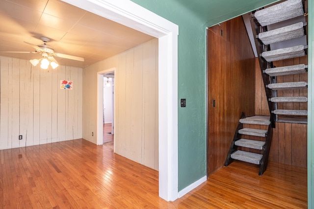 hall with wooden walls, stairway, and light wood finished floors