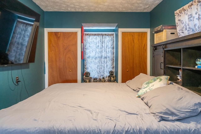 bedroom featuring a textured ceiling and two closets