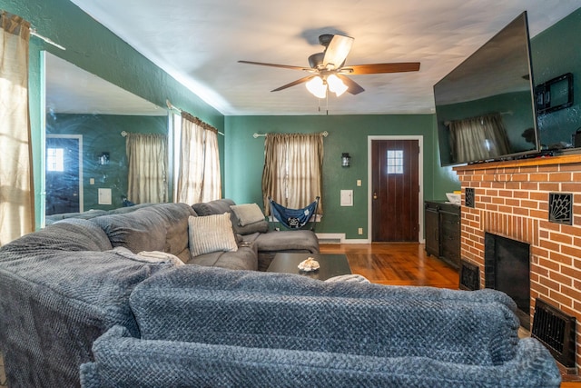 living room with ceiling fan, plenty of natural light, a fireplace, and wood finished floors