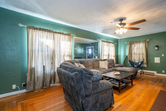 living room with a textured wall, ceiling fan, baseboards, and wood finished floors