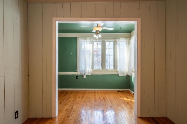 empty room with light wood-style floors, visible vents, ceiling fan, and baseboards