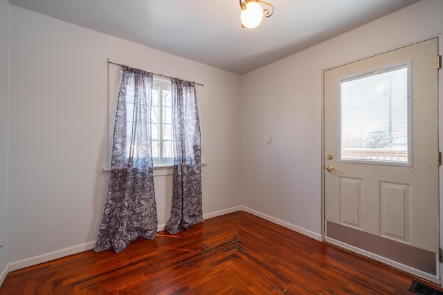 unfurnished room with dark wood-style floors, visible vents, and baseboards