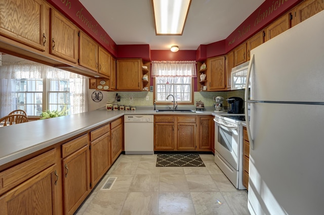 kitchen featuring visible vents, a sink, brown cabinetry, white appliances, and open shelves