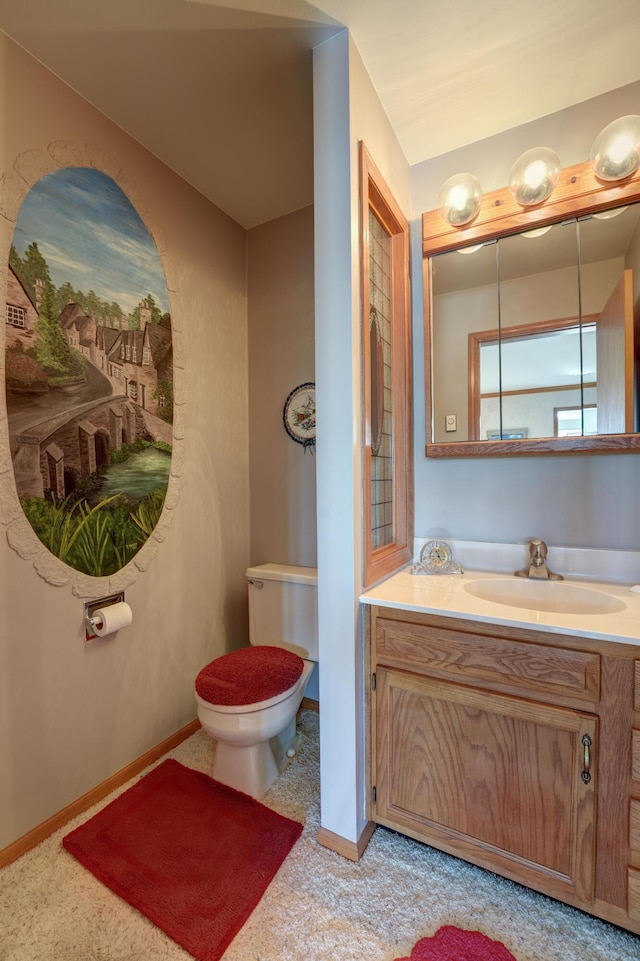 half bathroom featuring vanity, toilet, and baseboards