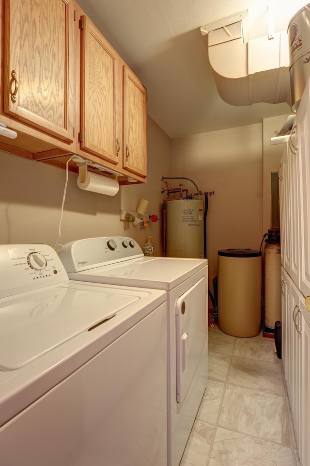 washroom with cabinet space, washing machine and dryer, and water heater