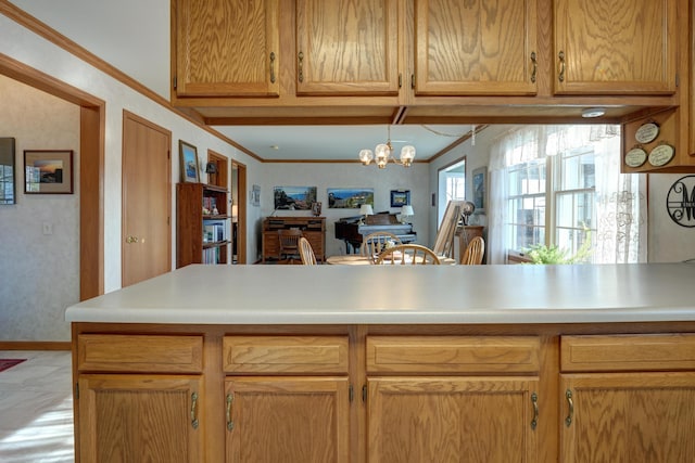 kitchen with light countertops, a notable chandelier, baseboards, and ornamental molding