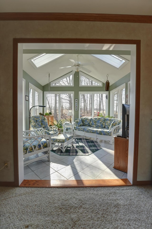 entryway with tile patterned flooring, lofted ceiling with skylight, a ceiling fan, and carpet floors