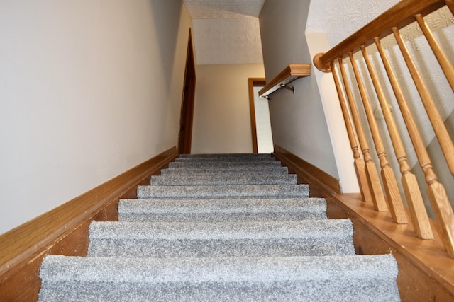 stairs featuring baseboards and a textured ceiling