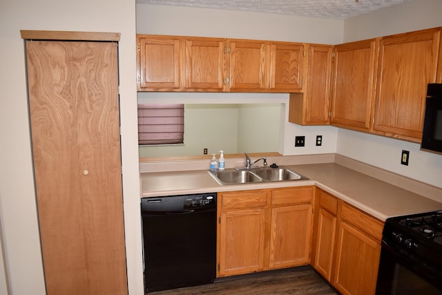 kitchen featuring brown cabinetry, light countertops, a textured ceiling, black appliances, and a sink