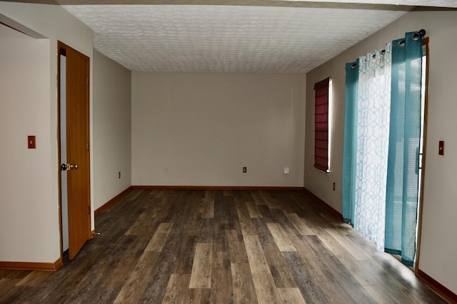 unfurnished room with baseboards, dark wood finished floors, and a textured ceiling