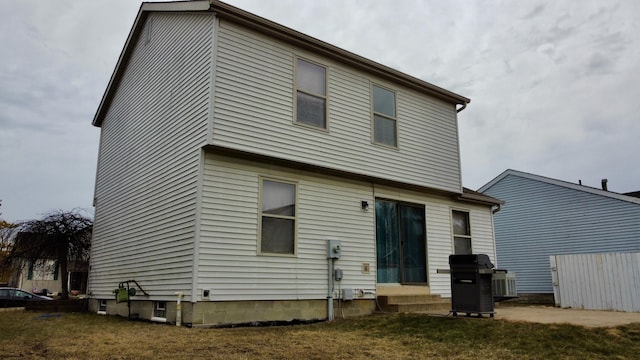 rear view of house featuring entry steps and a yard