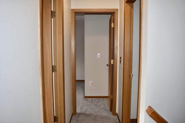 hall with baseboards and light colored carpet