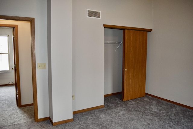 unfurnished bedroom with dark colored carpet, visible vents, and baseboards