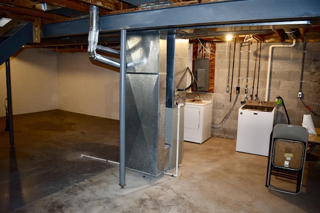 unfinished below grade area featuring independent washer and dryer, electric panel, and heating unit