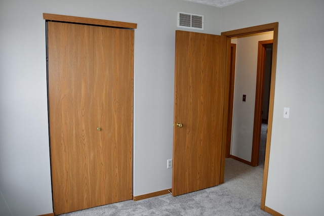 unfurnished bedroom featuring light colored carpet, a closet, visible vents, and baseboards