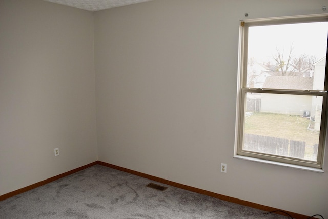 spare room featuring carpet flooring, visible vents, and baseboards