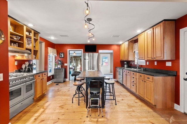 kitchen featuring a kitchen bar, sink, light hardwood / wood-style flooring, a kitchen island, and stainless steel appliances