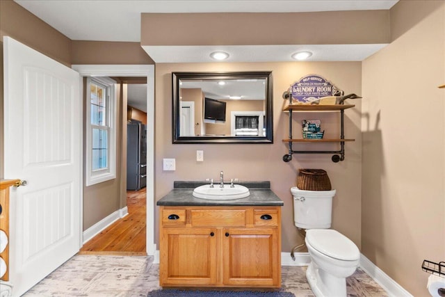 bathroom featuring vanity, wood-type flooring, and toilet