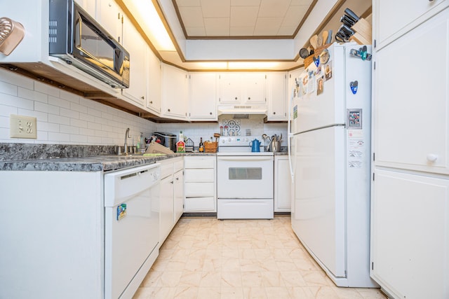 kitchen with tasteful backsplash, dark countertops, white cabinets, white appliances, and under cabinet range hood