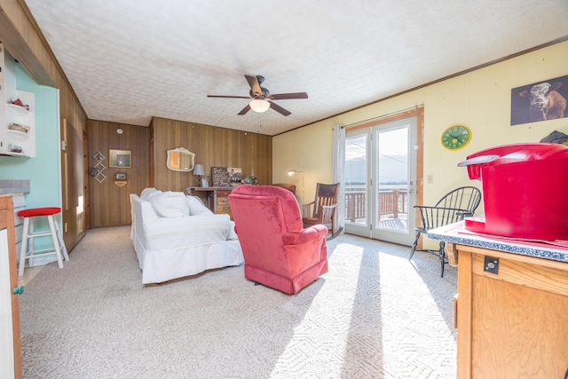 living area featuring light carpet, wood walls, ornamental molding, and a textured ceiling