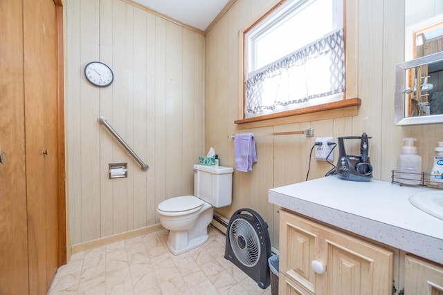 bathroom with baseboard heating, wood walls, vanity, and toilet