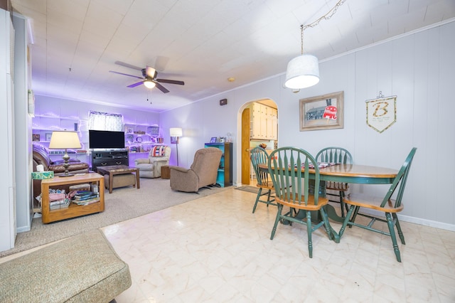 dining area with arched walkways, baseboards, a ceiling fan, and crown molding