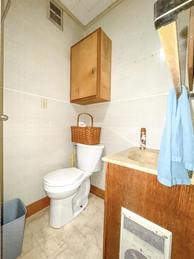 half bath featuring toilet, vanity, visible vents, and tile walls