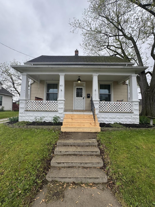411 Middle St, Wapakoneta, OH 45895 - view of front facade with covered porch, a chimney, a front yard, and roof with shingles