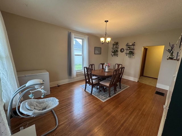 411 Middle St, Wapakoneta, OH 45895 - dining space featuring a chandelier, wood finished floors, a textured ceiling, and baseboards