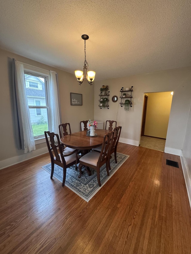 411 Middle St, Wapakoneta, OH 45895 - dining space featuring a chandelier, a textured ceiling, wood finished floors, and baseboards
