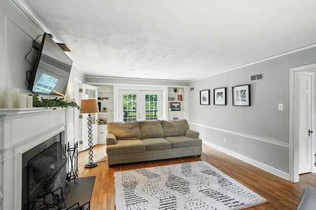 650 Swailes Rd, Troy, OH 45373 - living area with a fireplace, wood finished floors, french doors, built in shelves, and crown molding