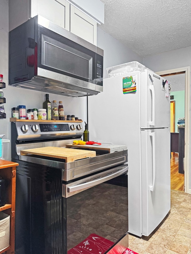 kitchen with white cabinetry, a textured ceiling, and appliances with stainless steel finishes