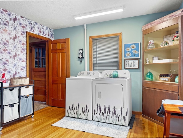 laundry room with laundry area, a textured ceiling, independent washer and dryer, light wood finished floors, and wallpapered walls