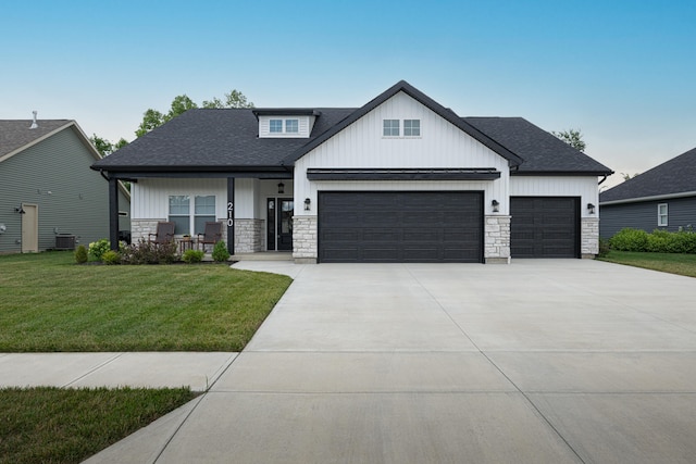210 N Branch, Tipp City, OH 45371 - modern farmhouse featuring an attached garage, stone siding, a front lawn, and covered porch