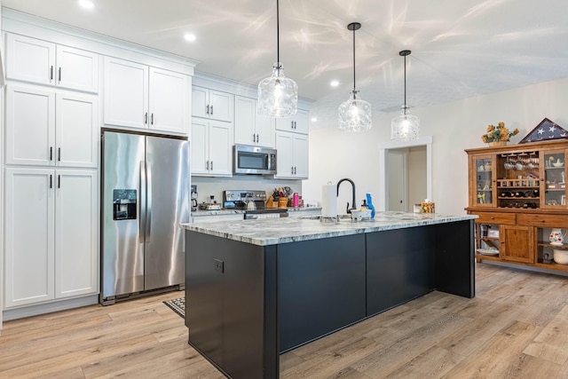 210 N Branch, Tipp City, OH 45371 - kitchen with stainless steel appliances, light wood-style flooring, white cabinetry, a center island with sink, and light stone countertops