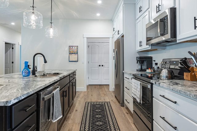 210 N Branch, Tipp City, OH 45371 - kitchen featuring appliances with stainless steel finishes, light wood-style flooring, light stone countertops, recessed lighting, and a kitchen island with sink