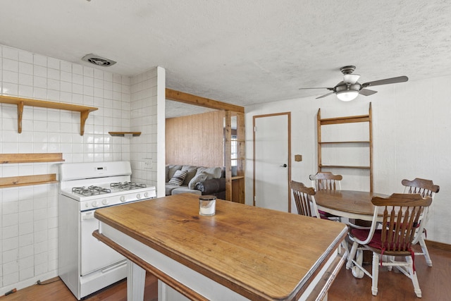 kitchen featuring ceiling fan, dark hardwood / wood-style flooring, gas range gas stove, and a textured ceiling