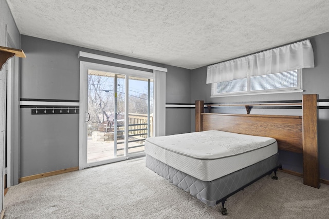 bedroom with a textured ceiling, light carpet, and access to outside