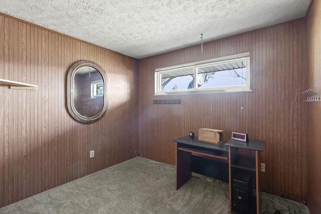 home office featuring carpet floors, a textured ceiling, and wood walls