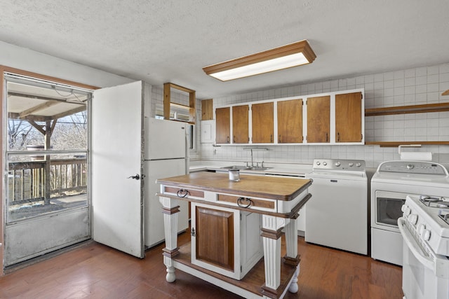 kitchen with white appliances, dark hardwood / wood-style flooring, decorative backsplash, and washing machine and clothes dryer