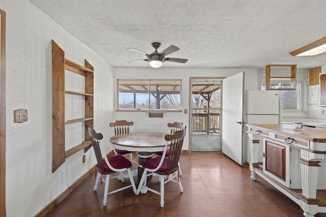 dining room featuring dark hardwood / wood-style flooring, ceiling fan, and a textured ceiling