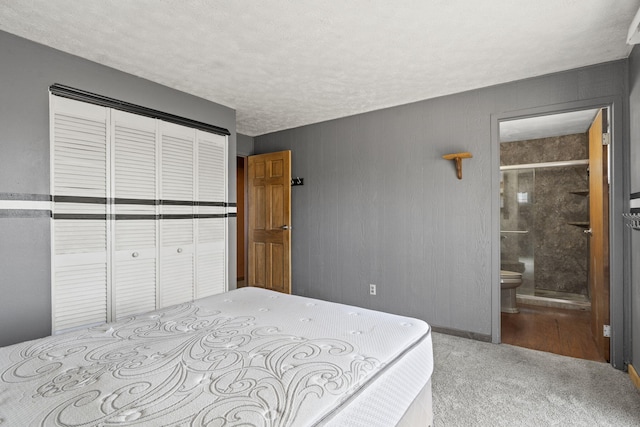 carpeted bedroom featuring connected bathroom, a closet, and a textured ceiling